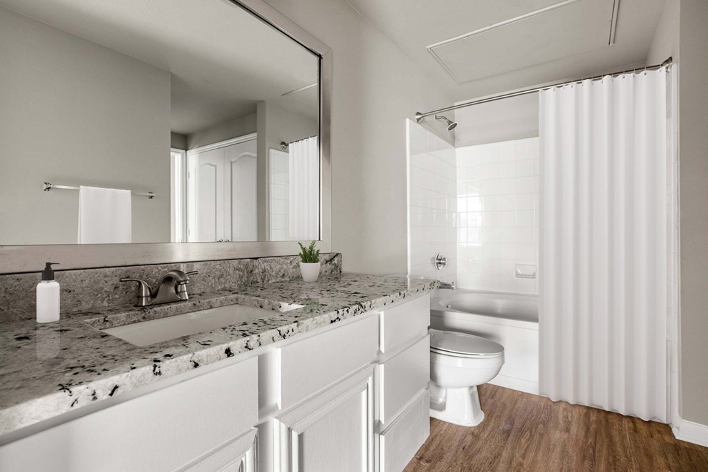 A modern bathroom with a marble countertop and white fixtures.