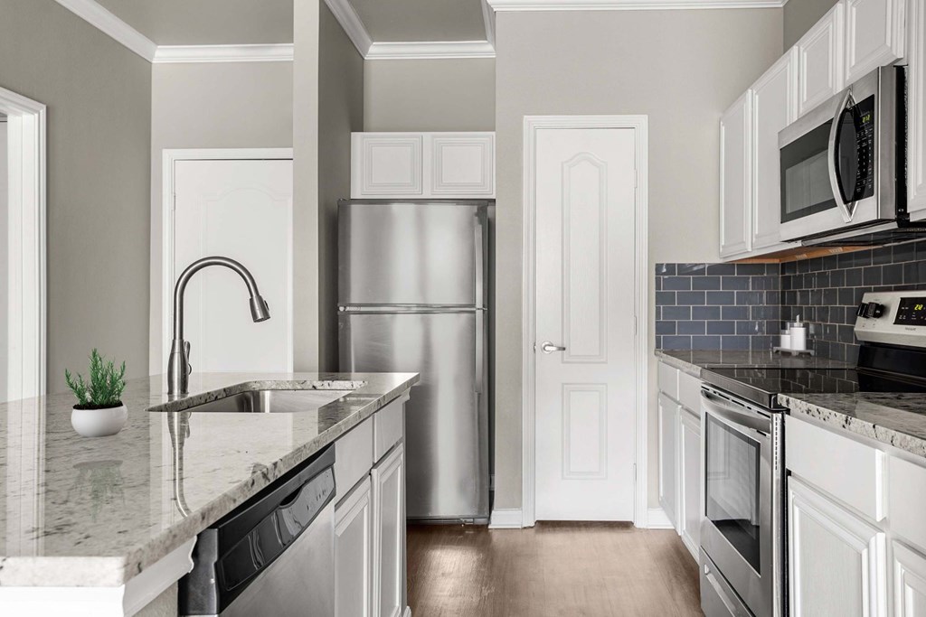 A kitchen with a refrigerator, sink, and oven.