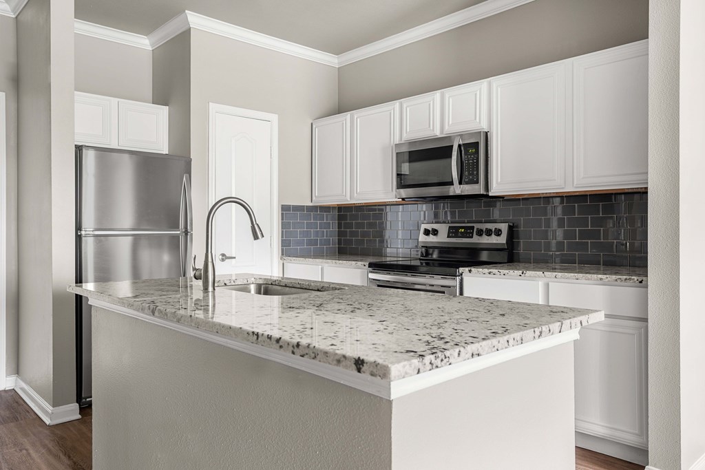 A kitchen with a marble countertop and stainless steel appliances.