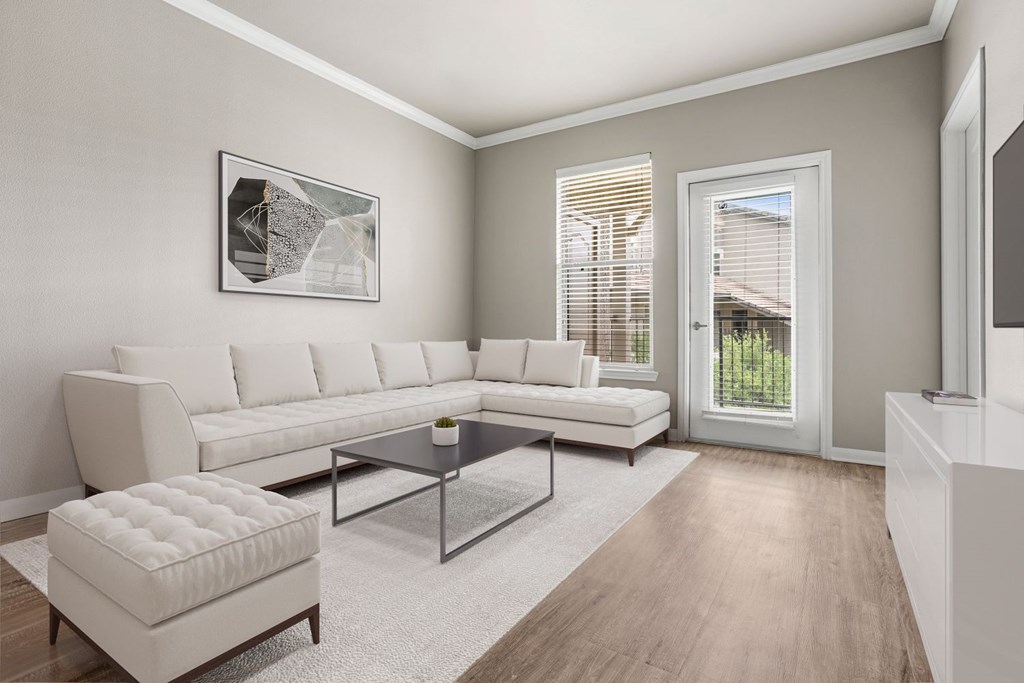 A modern living room with a white sofa, a coffee table, and a white ottoman.