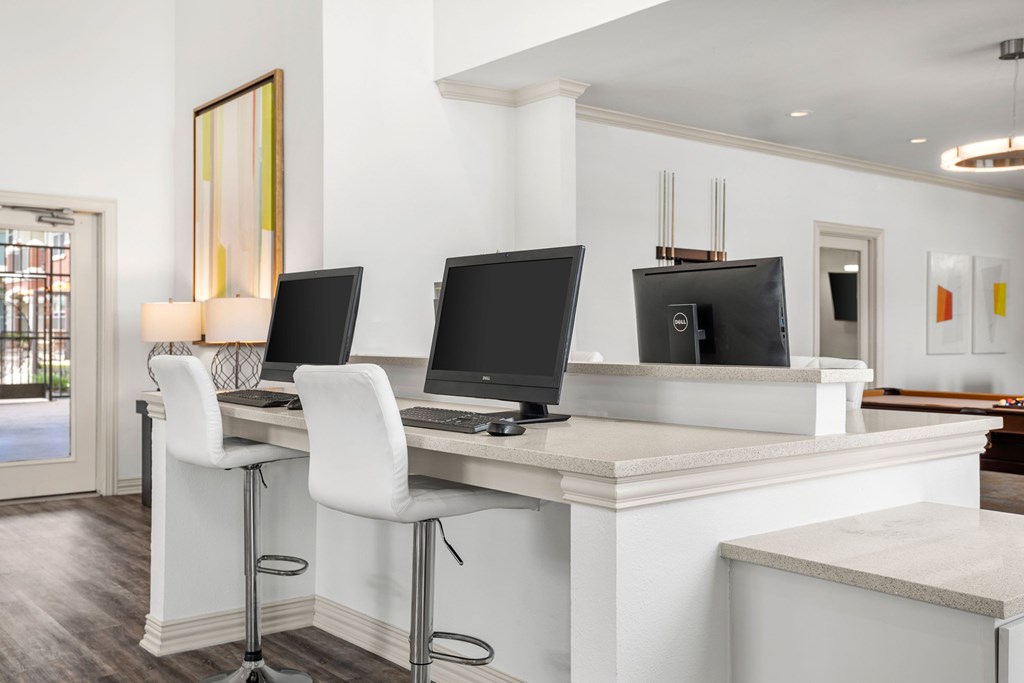 A white desk with two monitors and a laptop.