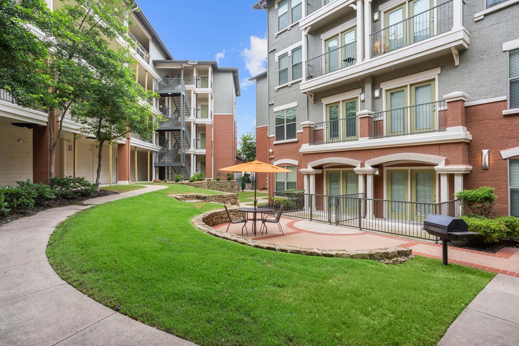 A sunny day at a residential complex with a green lawn and a small fountain.