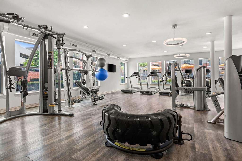 A gym with a variety of equipment including treadmills, weights, and exercise machines.