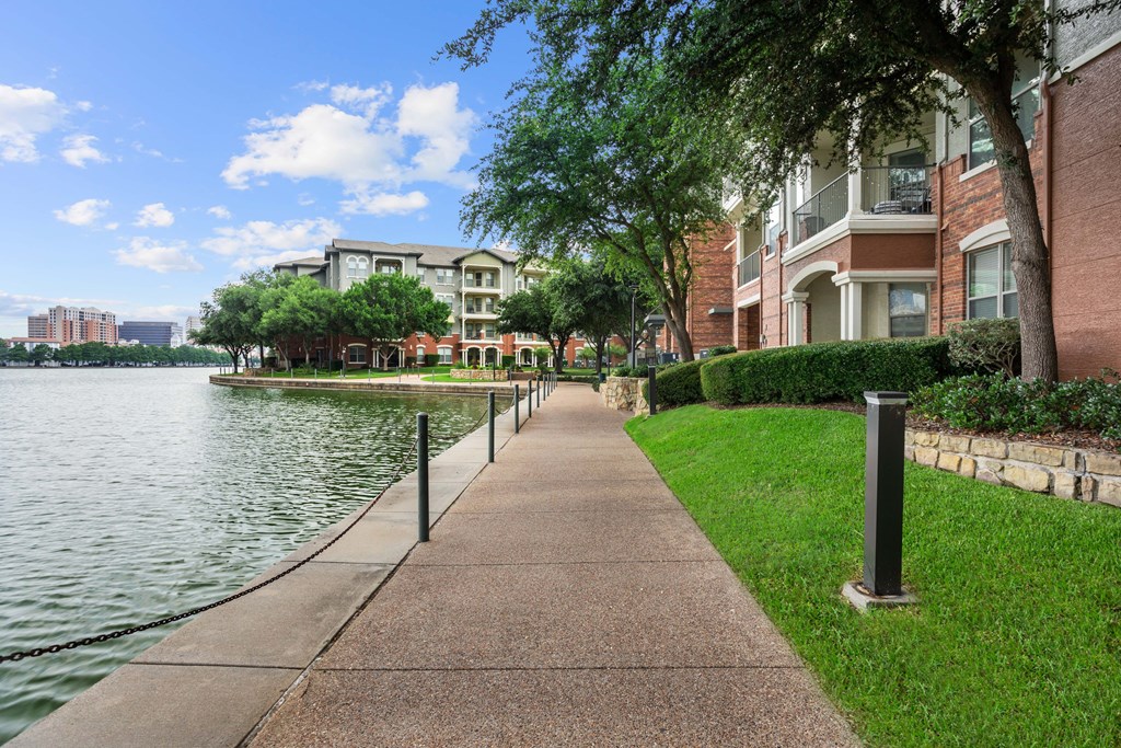 A walkway next to a body of water with a building in the background.