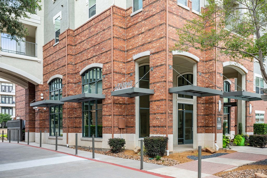A red brick building with a black awning and a white sign that says