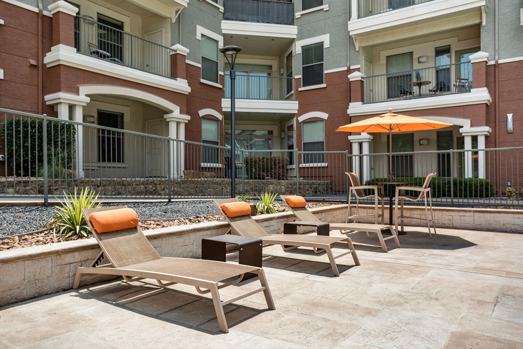 A patio with chairs and an umbrella in front of a building.
