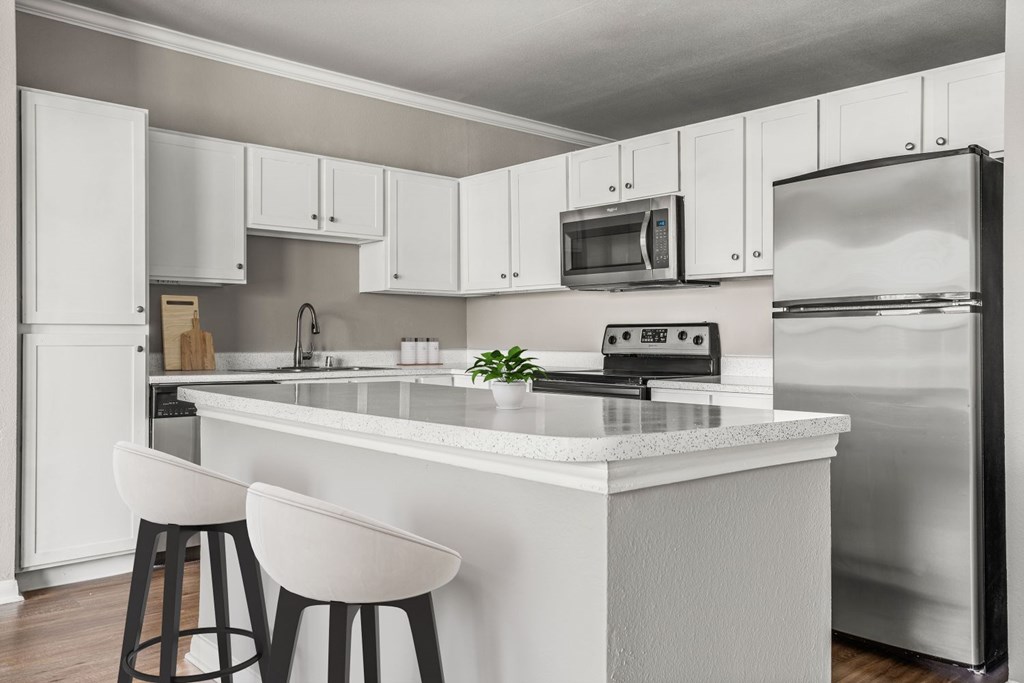A modern kitchen with white cabinets and a white island.