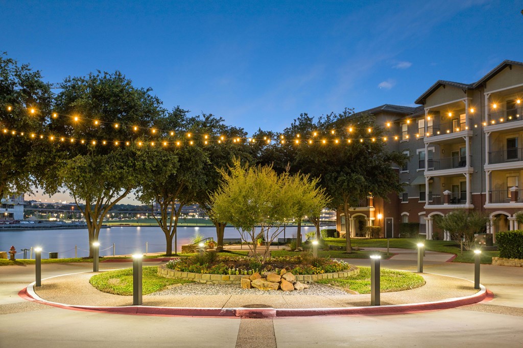 A beautifully lit garden in front of apartment buildings at dusk.