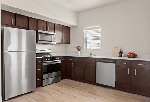 A modern kitchen with dark brown cabinets and stainless steel appliances.