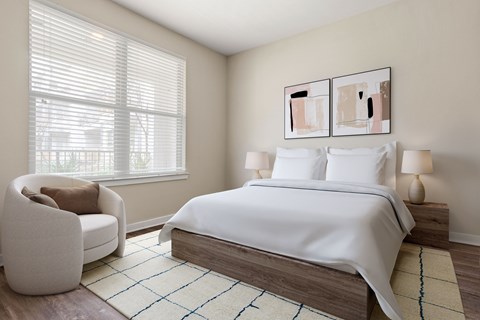 A bedroom with a large bed and a chair by the window.