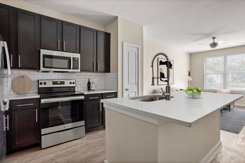 A modern kitchen with dark brown cabinets and stainless steel appliances.