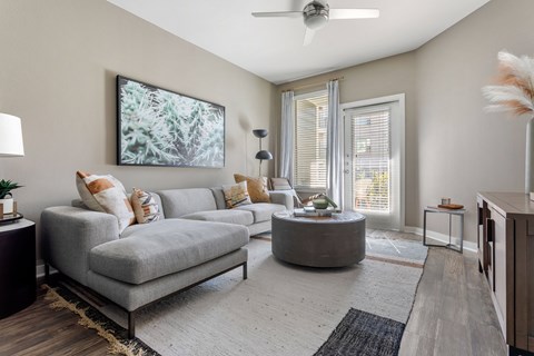 A living room with a grey sofa, a round coffee table, and a painting on the wall.