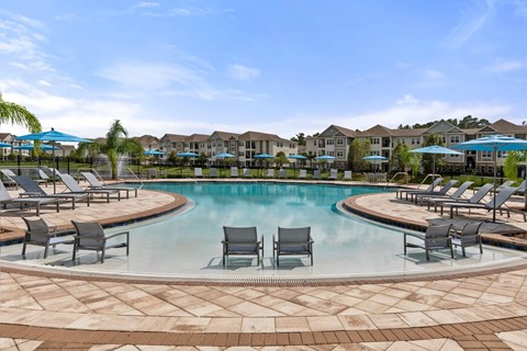 A large swimming pool surrounded by lounge chairs and umbrellas.
