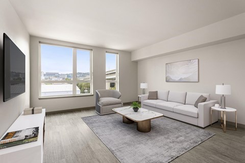 A modern living room with a grey rug, a white sofa, a grey armchair, a coffee table, and a painting on the wall.