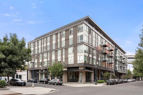 A modern multi-story building with a parking lot in front.