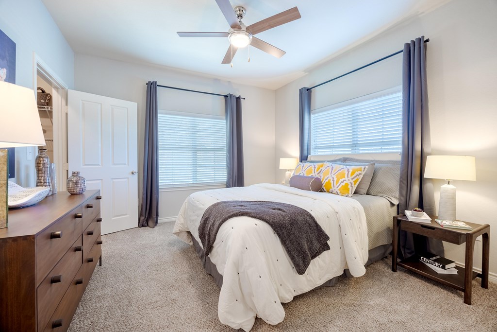 A bedroom with a bed, nightstand, and a ceiling fan.