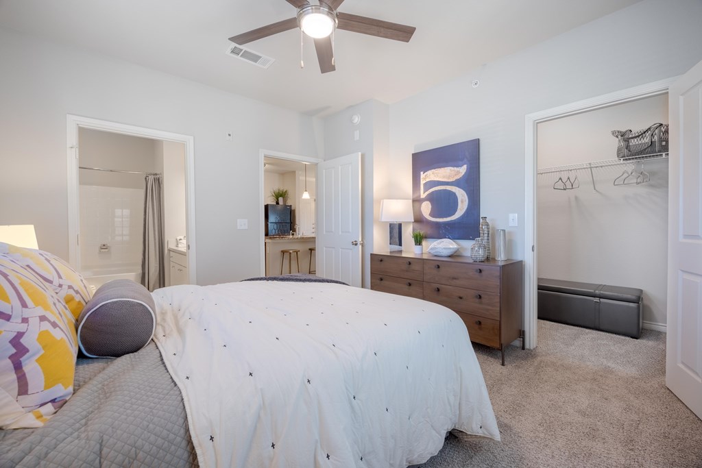 A bedroom with a bed, dresser, and a ceiling fan.