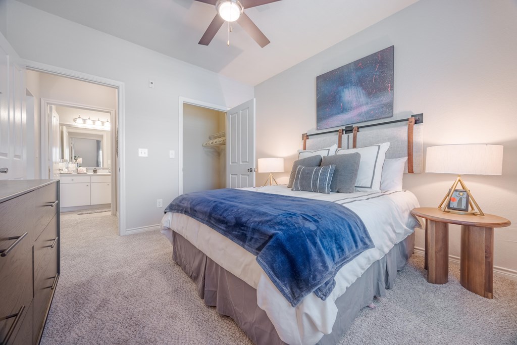 A bedroom with a bed, a dresser, and a ceiling fan.