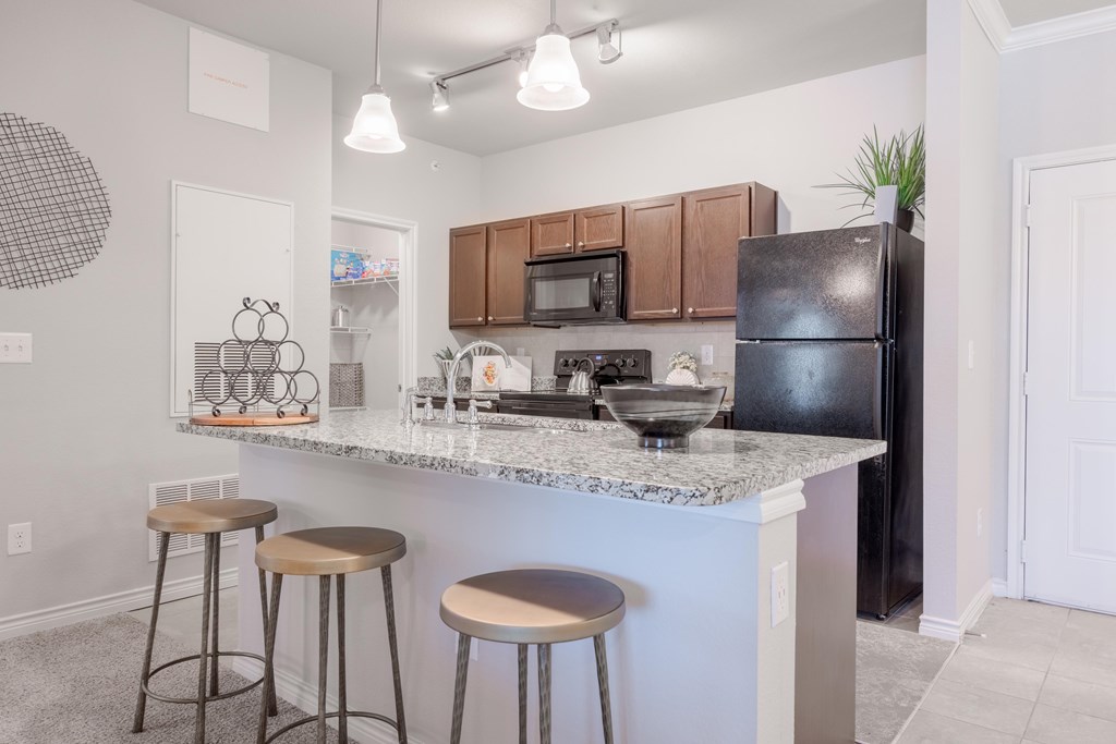 A kitchen with a black refrigerator and white countertops.