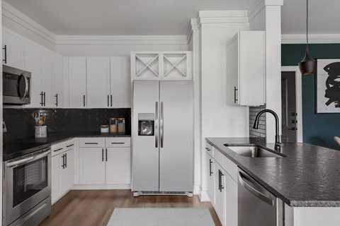 A kitchen with white cabinets and a black countertop.