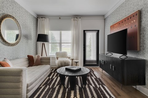 A modern living room with a white sofa, a black coffee table, and a television mounted on the wall.