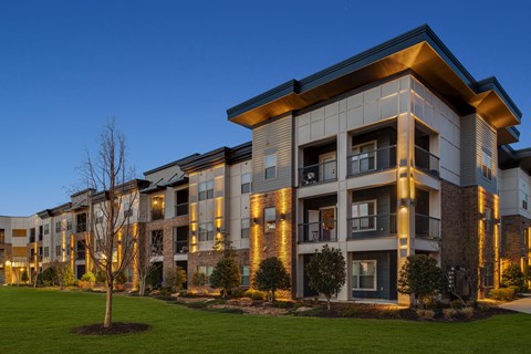 A modern apartment building with a well-maintained lawn in front.