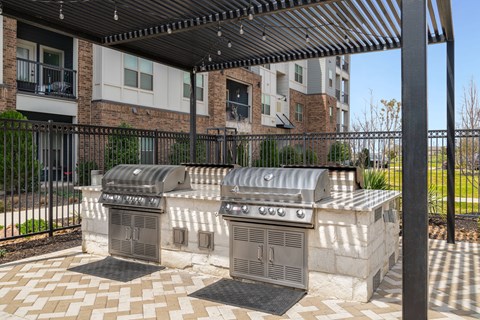 A black metal fence surrounds a stone grill area.