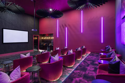 A room with red chairs and a white screen on the wall.