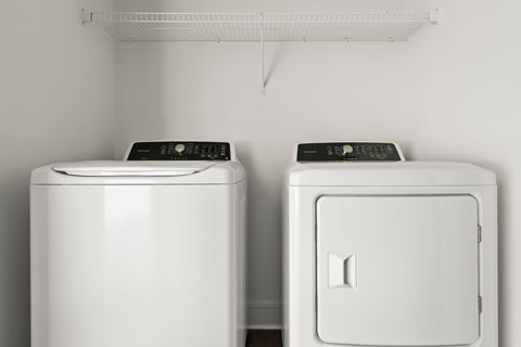 Two white front loading washing machines in a laundry room.