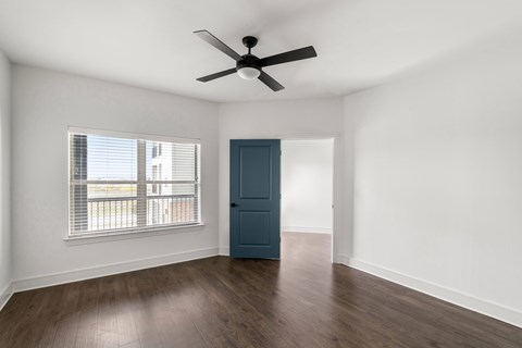 A room with a ceiling fan and a blue door.