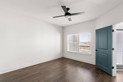 A room with a ceiling fan and a door.