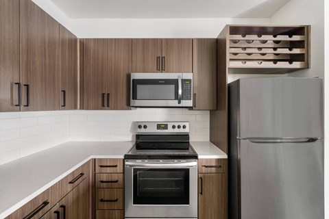 A modern kitchen with a stainless steel refrigerator, microwave, oven, and cabinets.