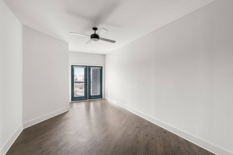A room with a ceiling fan and sliding glass doors.