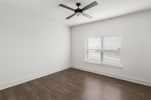 A room with a ceiling fan and a window with blinds.