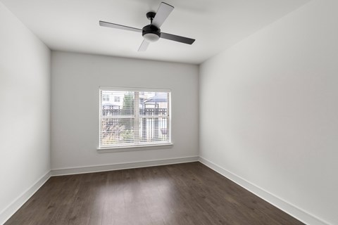 A room with a ceiling fan and a window with blinds.