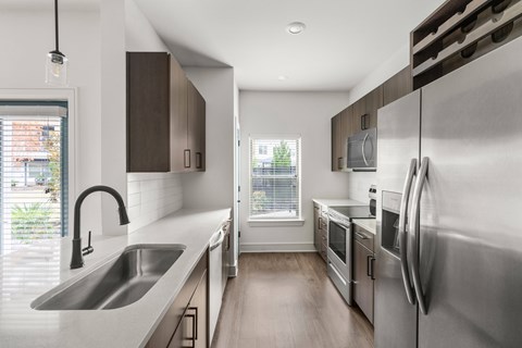 A modern kitchen with stainless steel appliances and a large window.