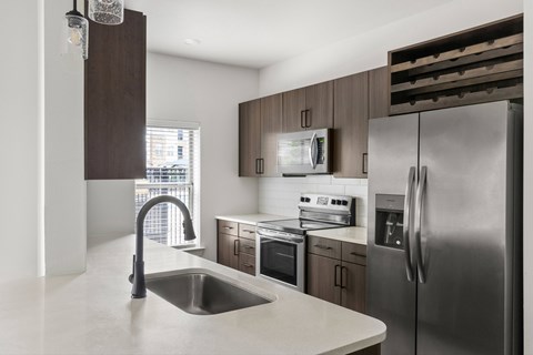 A modern kitchen with a stainless steel refrigerator and a sink.