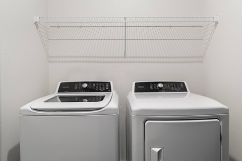 Two white front loading washing machines in a laundry room.