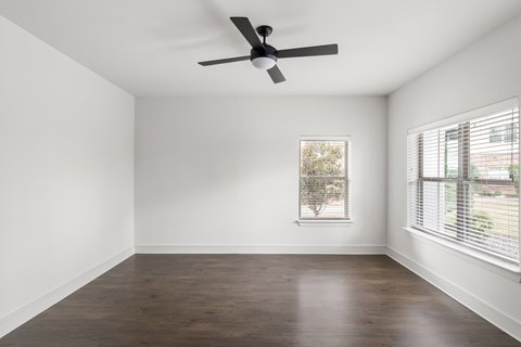 A room with a ceiling fan and a window with blinds.