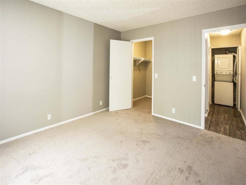 A room with a carpeted floor and two open closets.