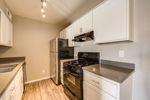 A kitchen with white cabinets and a black stove top oven.