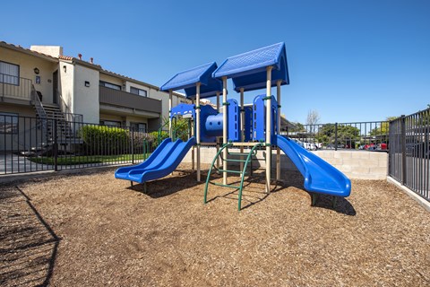 A playground with a blue slide and a blue canopy.
