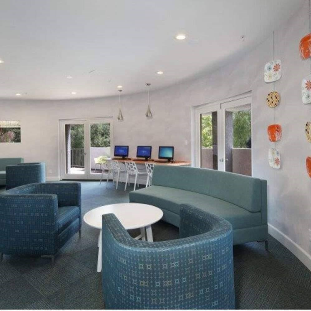 A room with a blue couch, chairs, and tables.