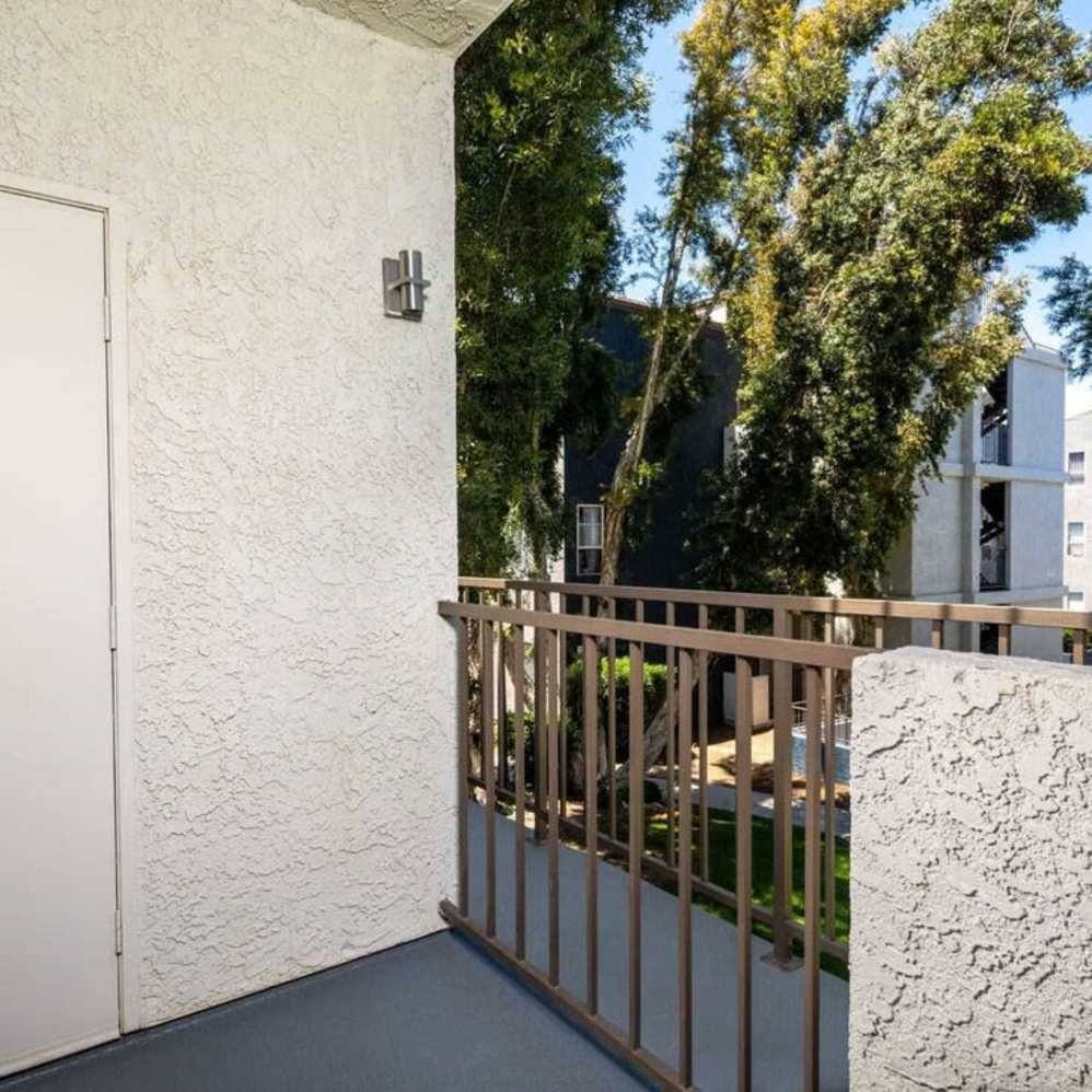A white wall with a door and a metal railing.