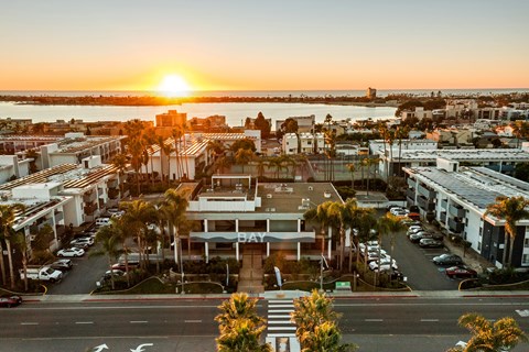 A sunset view of a city street with a building that has the word