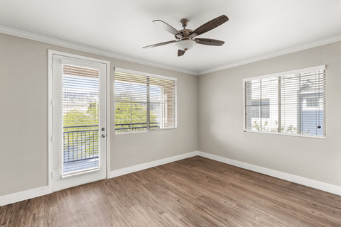 A room with a ceiling fan and two windows with blinds.