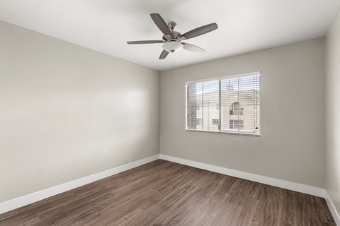 A room with a ceiling fan and a window with blinds.