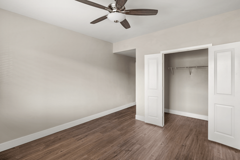 A room with a ceiling fan and a doorway leading to another room.