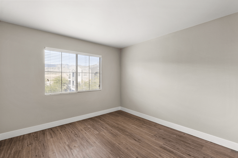 Empty room with wooden flooring and a window.