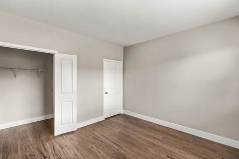 A room with a white door and a wooden floor.